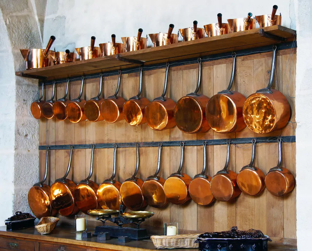 Large assortment of Copper Pots and Pans and Cookware hanging in kitchen